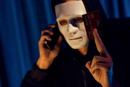 White criminal anonymous mask calling to credit card owner to threaten ransom with privacy information all database, making password encryption by programming hack trying to make insecure. Pecuniary.の写真素材