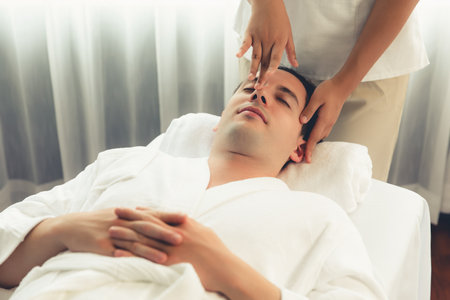 Caucasian man enjoying relaxing anti-stress head massage and pampering facial beauty skin recreation leisure in dayspa modern light ambient at luxury resort or hotel spa salon. Quiescentの写真素材