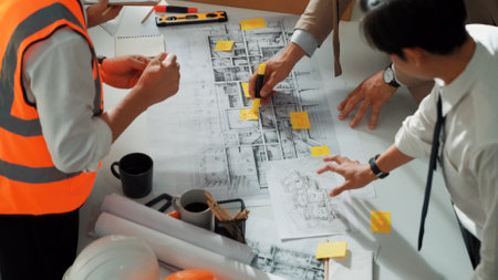 Top view of professional architect engineer team inspect house model while manager holding blueprint and asking about building construction. Group of diverse engineer working together. Alimentation.の写真素材