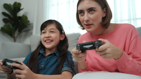 Caucasian mom and daughter sitting and playing game at living room. Happy mother spend time together...