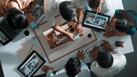 Top down view of manager pointing at house model and explain building design. Aerial view of architect engineer brainstorming about interior construction while tablet display house plan. Alimentation.の写真素材