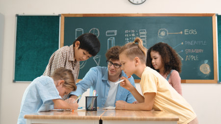 Smart teacher explain idea while diverse children drawing mind map while group of diverse student working together to do class work. Attractive instructor teaching and talking about working. Pedagogy.の写真素材