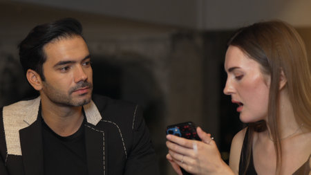 Portrait of focus beautiful woman talking with couple while looking at smartphone with serious face...
