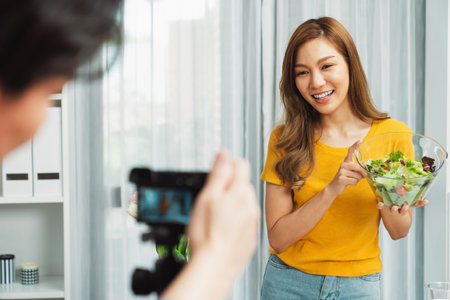 Asian beautiful woman food specialist blogger teaching how to mixed salad easy cooking in blow on live channel recorded blurred camera screen by cameraman streaming lifestyle social media. Infobahn.の写真素材