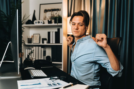 Sales manager working on desk with stretching arm up and down manner at night time at modern home office with monthly sales report for quarter presentation summary of profitable product. Pecuniary.の写真素材