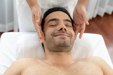 Caucasian man enjoying relaxing anti-stress head massage and pampering facial beauty skin recreation leisure in dayspa modern light ambient at luxury resort or hotel spa salon. Quiescentの写真素材