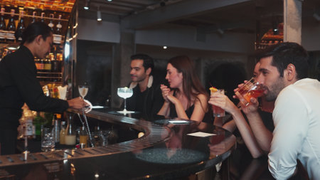 Couple making a toast with cocktail paloma and old fashioned at luxurious bar in lively conversation drinks celebrating a special party at vibrant nightclub while friend drinking Margarita. Vinosity.の写真素材