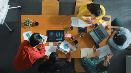 Top view of skilled businessman present marketing idea at meeting while group of investor listening and planning strategy while looking at stock market chart or data analysis document. Convocation.の写真素材