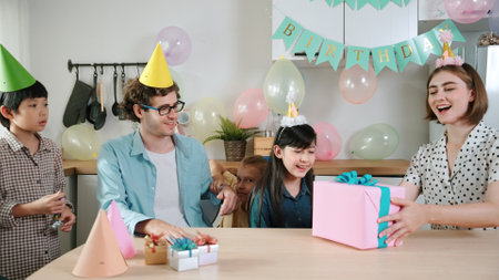 Attractive caucasian girl receive birthday present while her parent celebrate and wearing party hat....