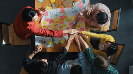 Top view of people writing and making scrum task board or kanban board while writing plan and planning strategy at colorful sticky notes. Team putting hand together and clapping hands. Convocation.の写真素材