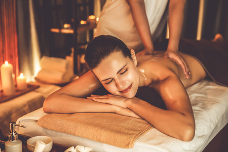Caucasian woman customer enjoying relaxing anti-stress spa massage and pampering with beauty skin recreation leisure in warm candle lighting ambient salon spa at luxury resort or hotel. Quiescentの写真素材