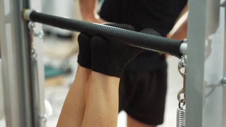 Pilates instructor guiding client foot placement during a reformer exercise for improving leg strength, and core stability. Close up of healthy girl feet making lower and lift pose. Habituate.の写真素材