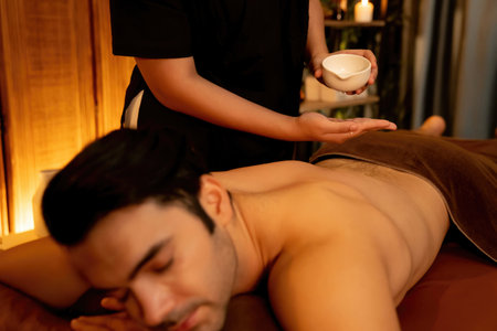 Masseur hands pouring aroma oil on man back. Masseuse prepare oil massage procedure for customer at spa salon in luxury resort. Aroma oil body massage therapy concept. Quiescentの写真素材