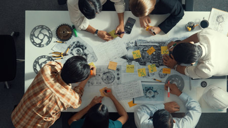 Top view of smart engineer team in casual cloth talking about turbine engine structure at table with metal gear, calculator, sticky notes. Group of technician taking a note in meeting. Alimentation.の写真素材