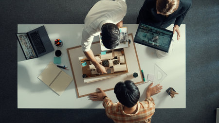 Top down view of manager pointing at house model and explain building design. Aerial view of architect engineer brainstorming about interior construction while tablet display house plan. Alimentation.の写真素材