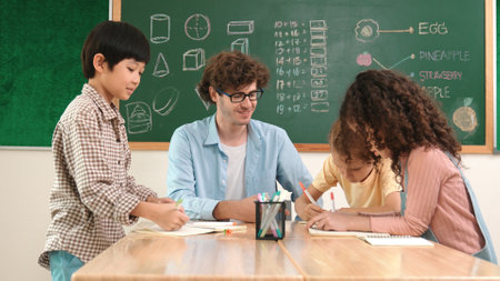 Smart teacher explain idea while diverse children drawing mind map while group of diverse student working together to do class work. Attractive instructor teaching and talking about working. Pedagogy.の写真素材