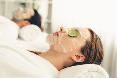 Serene daylight ambiance of spa salon, couple customer indulges in rejuvenating with luxurious cucumber facial mask. Facial skincare treatment and beauty care concept. Quiescentの写真素材