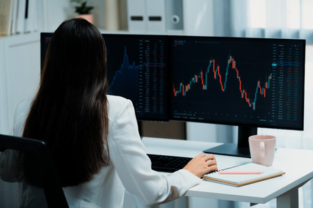Young beautiful Asian businesswoman looking on pc to analyze profitable of exchange stock market...