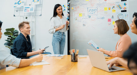 Young beautiful leader presents marketing strategy while expert investor and project manager lecturing to analyze business performance at start up business meeting. Multiethnic group. Immaculate.の写真素材