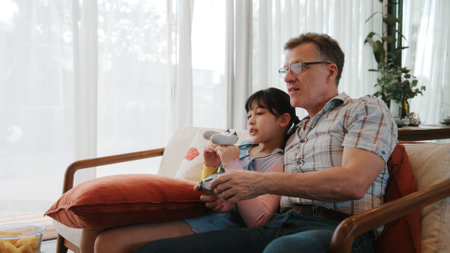 Grandfather and granddaughter together play console game, entertainment media. Old senior use...