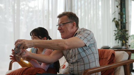 Grandfather and granddaughter together watch interesting entertainment media on TV. Old senior use technology communicate with young generation cross generation gap strengthen family bond. Divergence.の写真素材