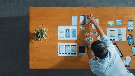 Top view of skilled developer walking and placing Ux Ui software. Smart business man put tablet on meeting table with mobile phone interface or icon. Investor plan develop software plan. Convocation.の写真素材