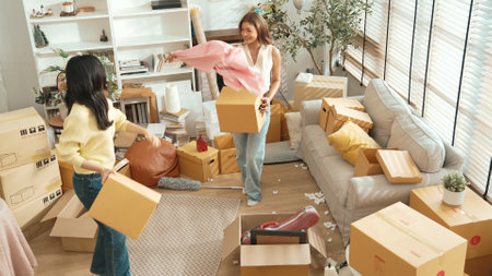 Top view of happy couple dancing together while carrying cardboard box in moving day. Attractive...