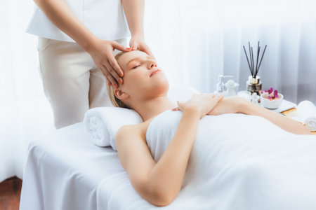 Caucasian woman enjoying relaxing anti-stress head massage and pampering facial beauty skin recreation leisure in dayspa modern light ambient at luxury resort or hotel spa salon. Quiescentの写真素材