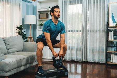 Athletic body and active sporty man doing squat with kettlebell weight for effective targeting muscle gain at gaiety home as concept of healthy fit body home workout lifestyle.の写真素材