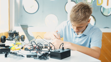 Caucasian boy fixing main board while study construction by using laptop analysis data. Young...