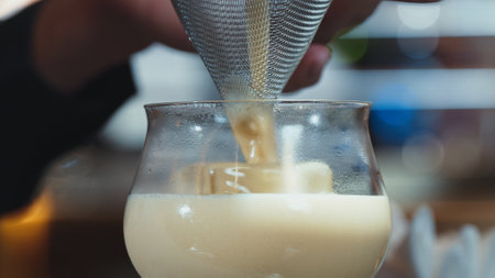 Closeup hand bartender using strainer in all ingredients alcohol liquor and syrup tasty in cocktail glass serving special refresh drink showcasing nightlife mixology at luxurious nightclub. Vinosity.の写真素材