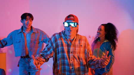 Diverse happy people moving to lively music with neon light at studio. Attractive hipster dancing while asian man show energetic movement while multicultural team cheering and supporting. Regalement.の写真素材