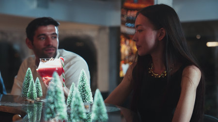 Group friend or couple talking fronted luxurious counter bar with mixed punch cocktail Christmas theme garnished candy cane to woman tasting in decorated snow Christmas tree in special time. Vinosity.の写真素材