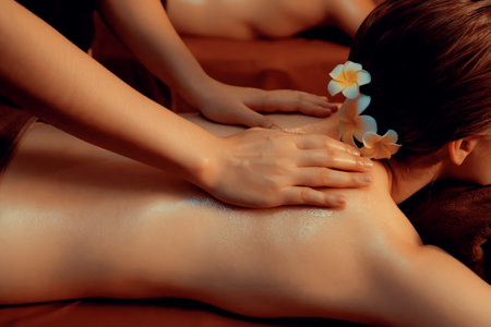 Caucasian couple customer enjoying relaxing anti-stress spa massage and pampering with beauty skin recreation leisure in warm candle lighting ambient salon spa at luxury resort or hotel. Quiescentの写真素材