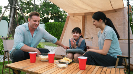 Family all together sit at camp in garden with tasty snack. Lovely parent use outdoor camping activity as way to communicate and spending time with young generation cross generation gap. Divergence.の写真素材