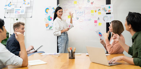 Young beautiful leader presents marketing strategy while expert investor and project manager lecturing to analyze business performance at start up business meeting. Multiethnic group. Immaculate.の写真素材