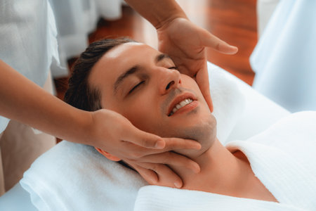 Caucasian man enjoying relaxing anti-stress head massage and pampering facial beauty skin recreation leisure in dayspa modern light ambient at luxury resort or hotel spa salon. Quiescentの写真素材