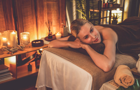 Caucasian woman customer enjoying relaxing anti-stress spa massage and pampering with beauty skin recreation leisure in warm candle lighting ambient salon spa at luxury resort or hotel. Quiescentの写真素材