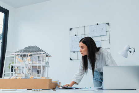 Portrait of Young beautiful caucasian architect focus on comparing house structure between house...