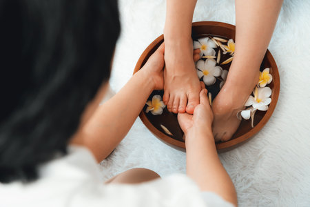 Woman indulges in blissful foot massage at luxurious spa salon while masseur give reflexology therapy in gentle day light ambiance resort or hotel foot spa. Quiescentの写真素材