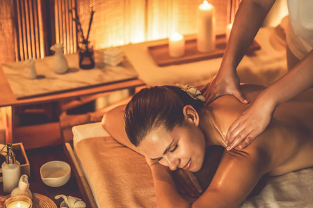 Caucasian woman customer enjoying relaxing anti-stress spa massage and pampering with beauty skin recreation leisure in warm candle lighting ambient salon spa at luxury resort or hotel. Quiescentの写真素材