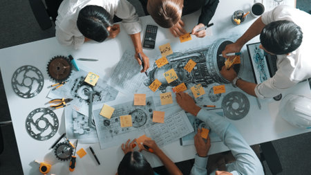 Top view of smart engineer team in casual cloth talking about turbine engine structure at table with metal gear, calculator, sticky notes. Group of technician taking a note in meeting. Alimentation.の写真素材