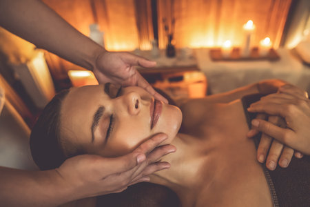 Caucasian woman enjoying relaxing anti-stress head massage and pampering facial beauty skin recreation leisure in warm candle lighting ambient salon spa in luxury resort or hotel. Quiescentの写真素材