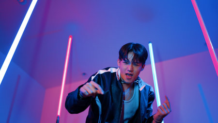 Low angle camera of professional street dancer looking at camera with casual cloth. Skilled performer moving to city pop music while standing at studio with purple led light. Close up. Regalement.の写真素材