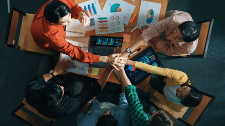 Top down view of business team putting hand together while discussing about Ux Ui design for mobile...