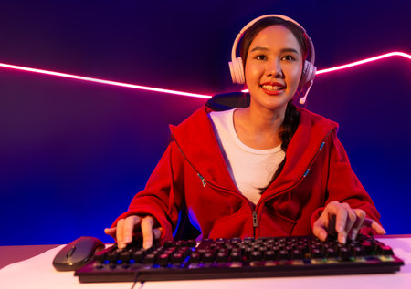 Host channel of smiling beautiful Asian girl streamer playing online game wearing headphone talking...
