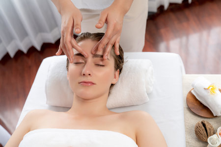 Caucasian woman enjoying relaxing anti-stress head massage and pampering facial beauty skin recreation leisure in dayspa modern light ambient at luxury resort or hotel spa salon. Quiescentの写真素材