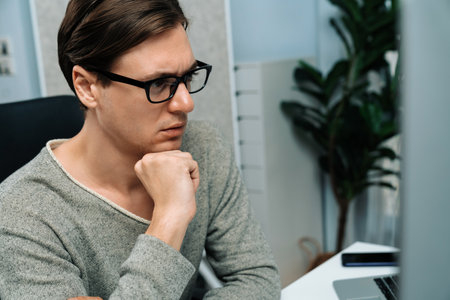Stressful office worker concentrating business report on pc, analyzing market strategy planning to...