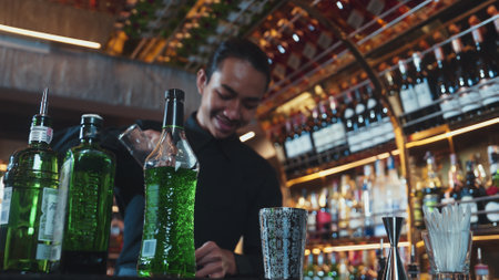 A person pouring mixed cocktail juice liqueur into a silver shaker, making a creative tasty drink, focused on refreshing showcase at a luxury bar.の写真素材