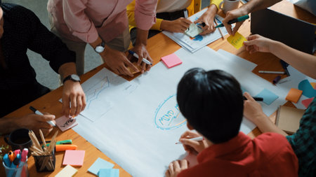 Top view of team in casual clothing writing ideas on sticky notes. People brainstorming while sticking colorful sticky notes on mind mapping.の写真素材